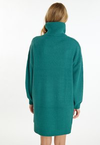 Abito maglia oversize color turchese con colletto alto, caratterizzato da motivi texturizzati e polsini e orlo a coste.