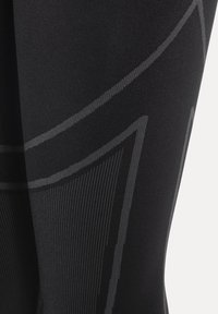 Czarne legginsy z teksturowaną, dopasowaną tkaniną. Zawierają szare geometryczne wzory i akcentujące linie, podkreślające smukły design.