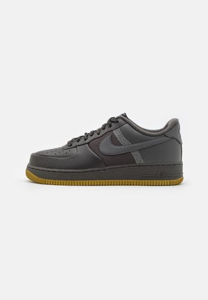 Lavtop sort og mørkegrå sneaker med tekstureret læder, reflekterende Nike swoosh, sorte snørebånd og gummisål.
