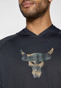 Schwarzes Sportshirt mit Kapuze, das an der Vorderseite ein strukturiertes, camouflage-muster Bullenkopf-Graphic in Grün und Beige zeigt, mit verstärkten Nähten.