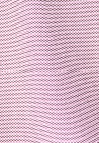 Tissu rose avec un motif répétitif de petits points circulaires créant une apparence texturée.