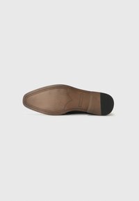 Semelle de chaussure en cuir marron avec une texture lisse, une forme effilée et des coutures détaillées. Comprend une grip en caoutchouc noir au talon pour une meilleure traction.