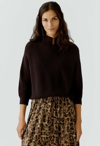 Bruine gebreide trui met een hoge hals en driekwartmouwen, gecombineerd met een rok met luipaardprint en een gathered taille.
