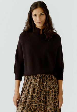 Bruine gebreide trui met een hoge hals en driekwartmouwen, gecombineerd met een rok met luipaardprint en een gathered taille.