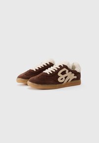 Brown suede sneakers with cream-colored fuzzy cuffs. Features white logo accent on the side and gum rubber sole. Classic athletic design.