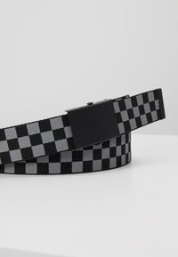 Zwart en grijs geblokt stoffen riem met een rechthoekige zwarte metalen gesp, voorzien van een gestructureerde weving en een slank, plat profiel.