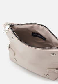 Pochette beige clair à fermeture éclair avec doublure en tissu, ouverte pour montrer l'intérieur et l'étiquette de marque noire "even&odd" à l'intérieur.