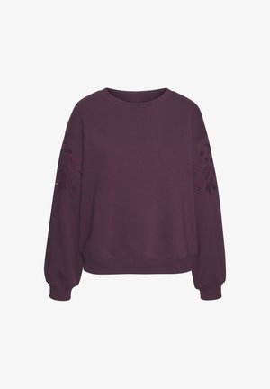 Vijolična dukserica z dolgimi rokavi, rebrastim ovratnikom in dekorativnim vezenjem na rokavih. Mehka textura in sproščen kroj.