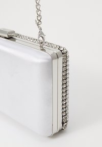 Silberne Satin-Clutch mit rechteckiger Form, verziert mit einem Strassbesatz und einem silbernen Kettenriemen. Kompakte Gestaltung.