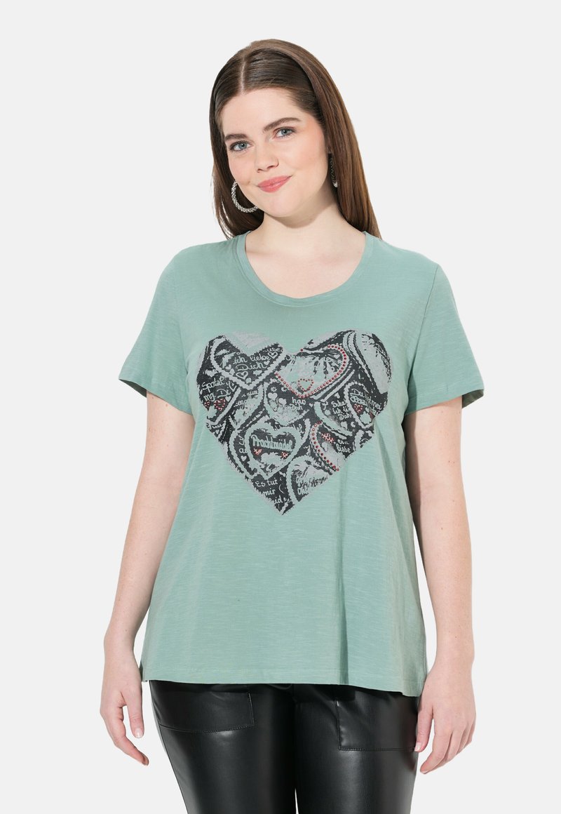 Lys grøn kortærmet t-shirt med et sort hjertegrafik med nænsomme mønstre og tekstdetaljer. Blødt stof med en afslappet pasform.