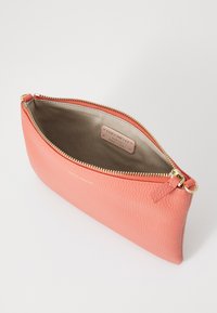 Peach leather pouch with a textured surface, gold-tone zipper, and a beige interior featuring a branded tag. Compact and oval shape.