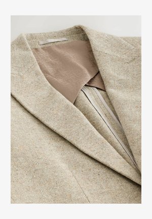Beige strukturierter Blazer mit Reverskragen und einem glatten, hellbraunen Futter. Verfügt über einen Reißverschluss und ein dezentes Muster innen.
