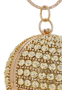 Gouden ronde handtas met een gestructureerd oppervlak met spiraalpatronen, versierd met strass-steentjes en een metalen ronde handgreep.