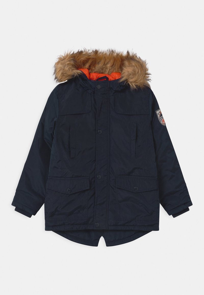 Parka d'hiver bleu marine avec doublure orange, bordure de capuche en fausse fourrure, poches avant, fermetures à boutons, et un écusson sur la manche gauche.