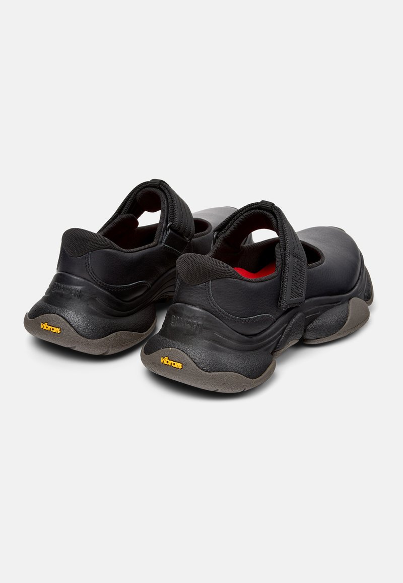 Scarpe nere con finitura testurizzata, fascia in Velcro e suola in gomma spessa con logo giallo Vibram. Progettate per comfort e stabilità.