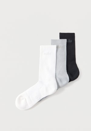 Kolm Nike soonelise soonusega crew-sokki valges, hallis ja mustas värvitoonis, üksteise peale asetatuna lihtsal heledal taustal.