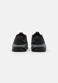 Musta urheilukengät, joissa on teksturoitu yläosa, harmaat yksityiskohdat ja kumipohja. Sisältää vetolenkin ja hienovaraisen swoosh-logon.