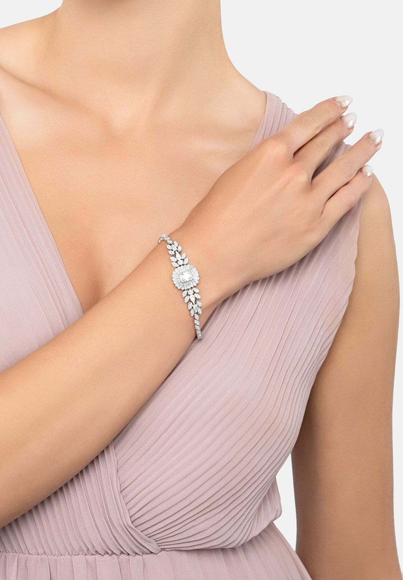 Diamond-studded bracelet featuring a floral design with a central round gem, silver-tone metal, and intricate leaf accents.