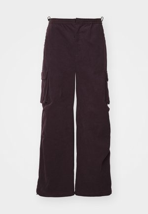 Kampuh lebar dengan saku samping berwarna ungu tua dari korduroi, dilengkapi dengan pinggang elastis dan jahitan minimal untuk memberikan kenyamanan yang santai.