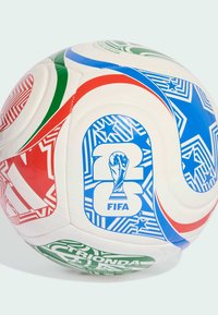 Balts futbols ar sarkaniem, zaļajiem un zilajiem rakstiem, kas veido zvaigžņu motīvu un FIFA logo. Tekstūrēta virsma, tipiska sfēriska forma.