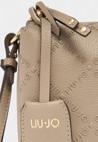 Borsa a mano in pelle color tan con motivo logo impresso, texture liscia, hardware dorato e tracolla regolabile.