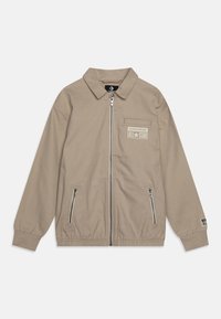 Beige zip-up jacka med krage, elastiska ärmslut, två sidofickor och en bröstlogga med "CONVERSE ALL-STAR."