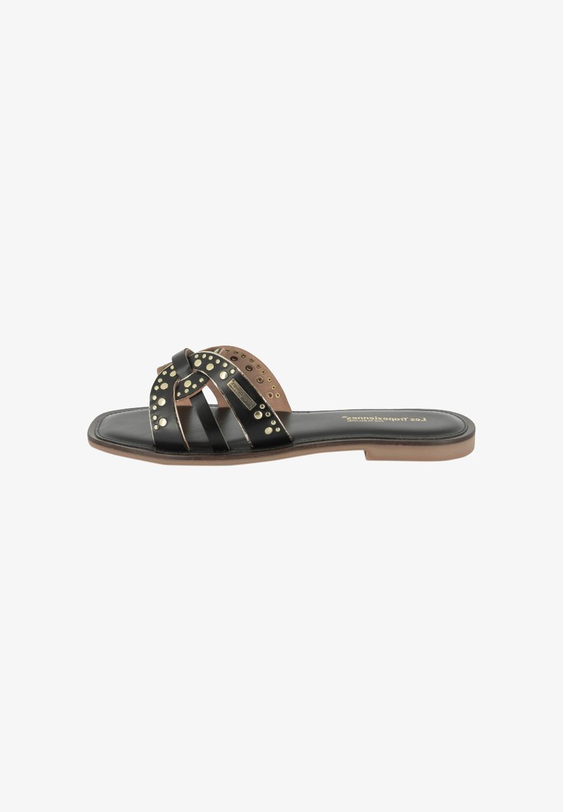 Chancla de cuero negro con un acento marrón, que presenta correas cruzadas adornadas con tachuelas doradas y una suela texturizada. Diseño de suela plana.