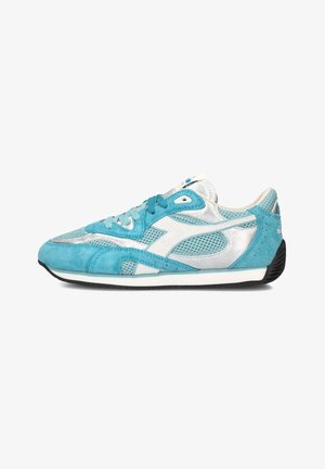 Chaussure de sport profilée en daim turquoise, panneaux en maille argentée, logo blanc et semelle noire vue de côté.