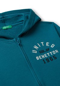 Felpa con zip color verde acqua, con interni testurizzati, caratterizzata da ricami "UNITED COL. OF BENETTON 1965" in bianco e nero.