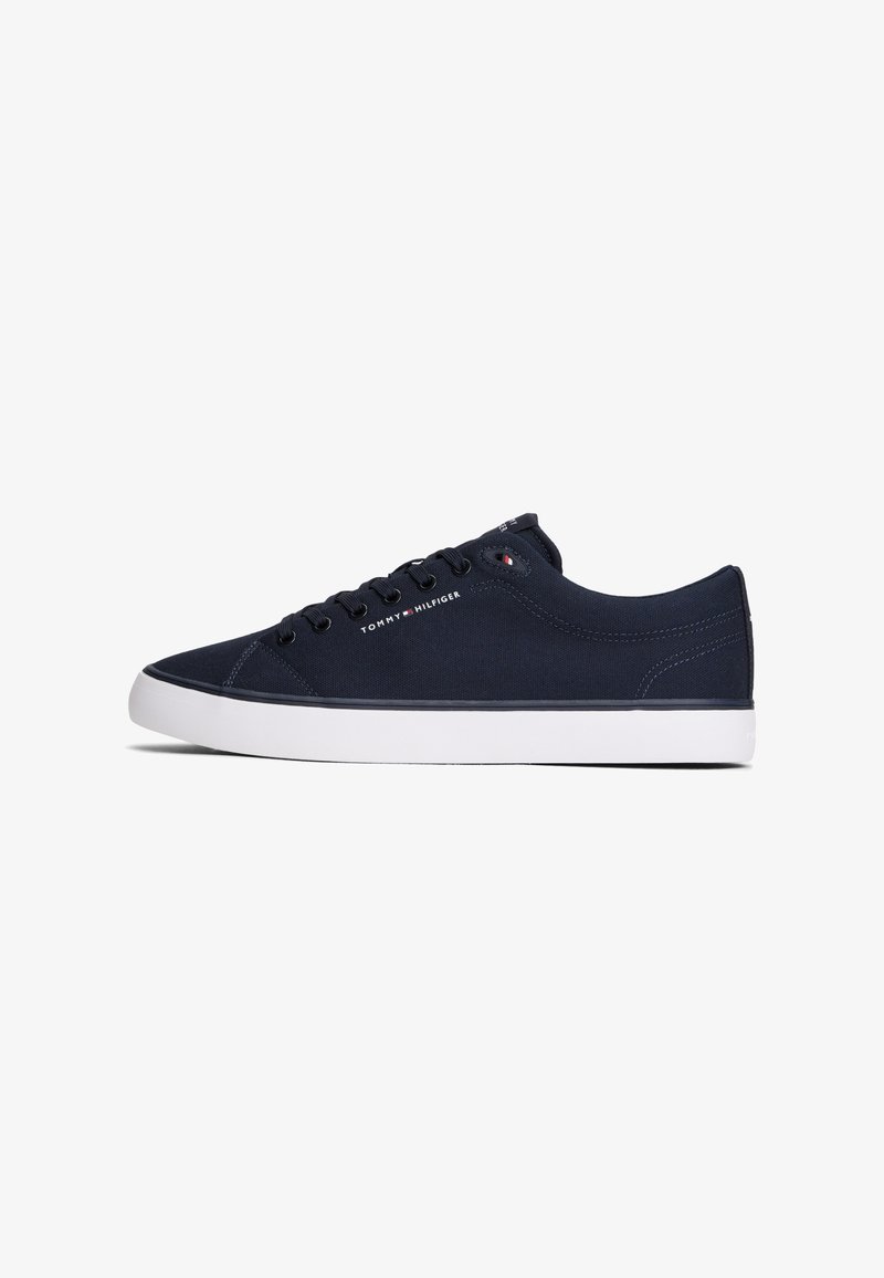 Baskets basses noires avec semelle blanche, lacets noirs et logo Tommy Hilfiger sur le côté et la languette.