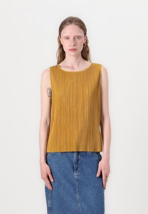 Sennepsgul ermeløs topp med vertikale folder, rund hals og rett skåret, sammen med et denimskjørt.