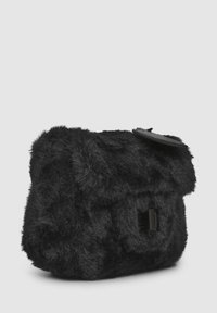 Borsa in pelliccia sintetica nera con una superficie morbida e strutturata. Presenta una chiusura a pattina e un piccolo tag rotondo. Forma rettangolare compatta.
