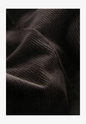 Tessuto in corduroy nero con righe distintive, caratterizzato da una superficie morbida e testurizzata e da leggere variazioni di luce e ombra.