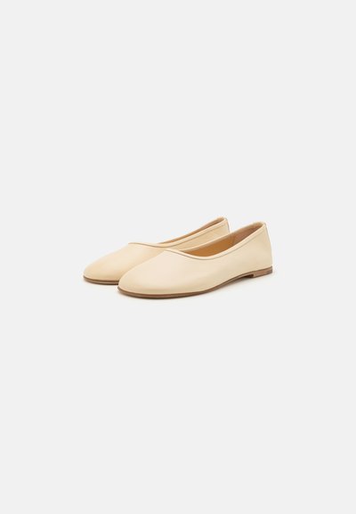 Ballerines beiges en cuir lisse, présentant un bout rond et un design minimaliste. Talon bas avec une semelle extérieure brune.