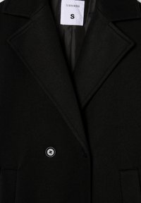 Czarny płaszcz z wełny z wykładanym kołnierzem, podwójnym zapięciem na guziki i przednimi kieszeniami. Etykieta informuje "Terranova", rozmiar "S".