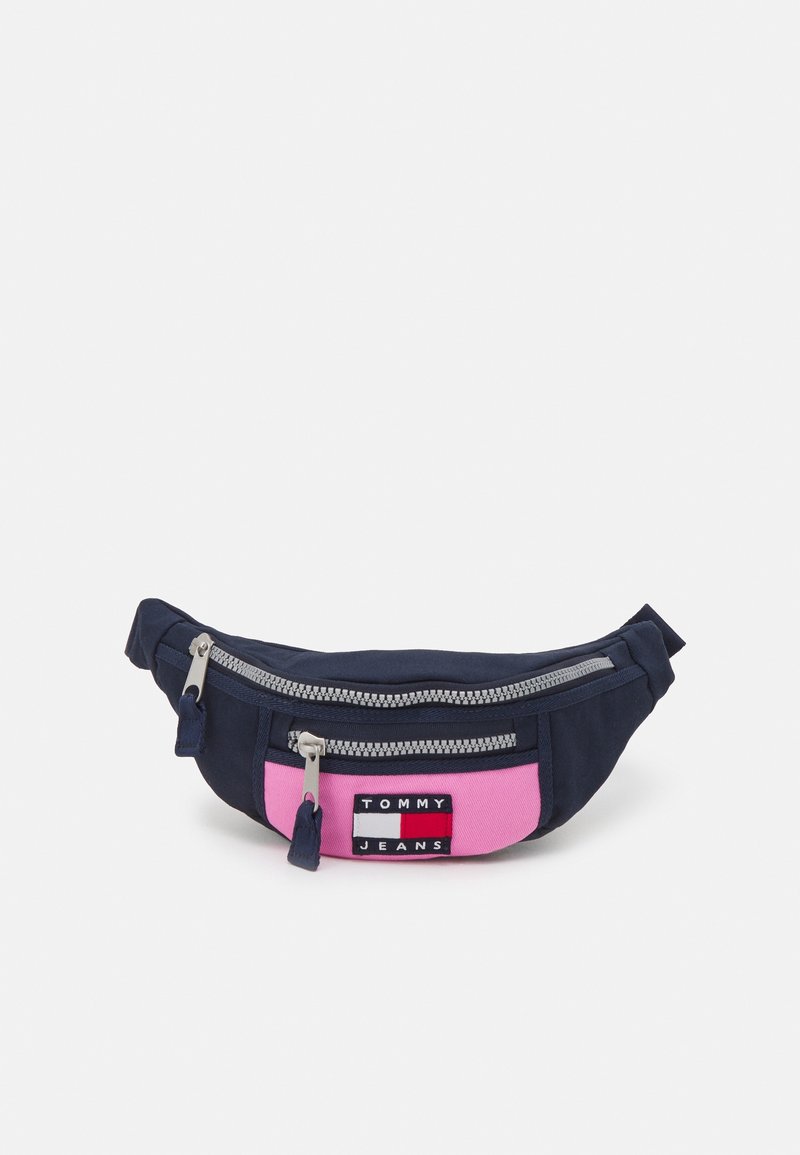 Marsupio in tessuto blu navy con pannello frontale rosa e zip argentata, caratterizzato da una toppa rettangolare con il testo "TOMMY JEANS".
