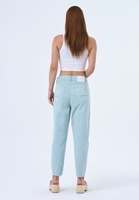 Lichtblauwe, high-waisted broeken met een losse pasvorm en twee achterzakken, voorzien van een wit logo-label op de tailleband. Gladde textuur.