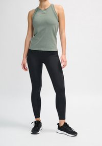 Gray fitted tank top with a rounded neckline, and black high-waisted leggings. Black athletic shoes with white soles. Plain background.