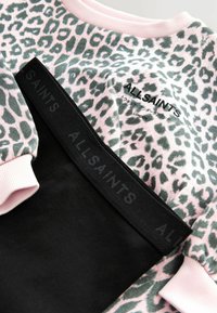 Rosa och grå leopardmönstrad sweatshirt med "ALLSAINTS LONDON" text och svarta leggings med midjeband med "ALLSAINTS" varumärke.