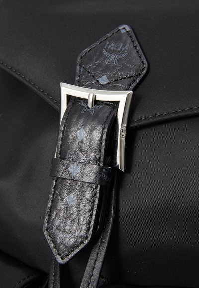 Geantă din nylon negru, prevăzută cu o curea din piele texturată neagră, cu accesorii din metal argintiu. Cureaua are un model în diamant și detalii cu logo.