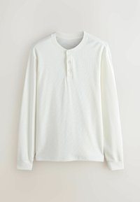 Camicia bianca a maniche lunghe tipo henley realizzata in tessuto testurizzato, con collo a girocollo, patta con tre bottoni e polsini a coste.
