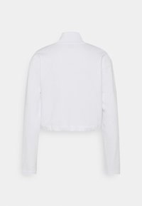 Haut blanc cropped à manches longues, avec un col montant, une texture douce et un ourlet arrondi. Design simple et dépouillé avec une esthétique épurée.