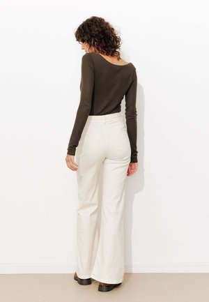Haut à manches longues, marron foncé avec un col large, associé à un pantalon évasé blanc taille haute. Design simple, texture lisse, sans motifs.