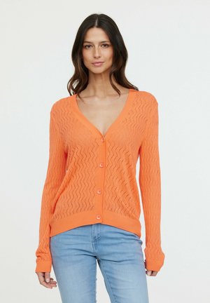Cardigan en tricot orange avec un col en V, présentant un motif en zigzag, un ourlet côtelé et des boutons sur le devant. Manches longues.
