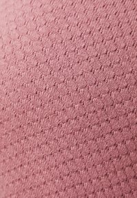 Tissu rose texturé avec un motif subtil de points en relief, présentant une apparence douce et tricotée ainsi qu'une finition lisse.