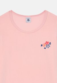 Light pink cotton T-shirt with a round neckline, featuring embroidered floral design in pink, blue, and yellow on the left chest area.