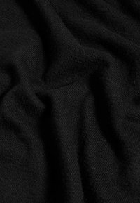 Tissu noir avec une surface douce et texturée, présentant des drapés et de légères variations dans le tissage, créant une apparence riche et stratifiée.