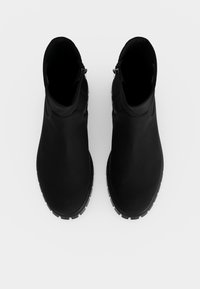 Paire de bottines en cuir noir avec fermetures éclair latérales et semelles robustes, vues de dessus sur fond blanc uni.