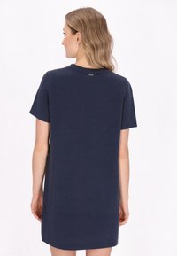 Abito blu navy a maniche corte con un design a maglia testurizzata, taglio dritto e piccolo dettaglio di branding sul retro vicino al collo.