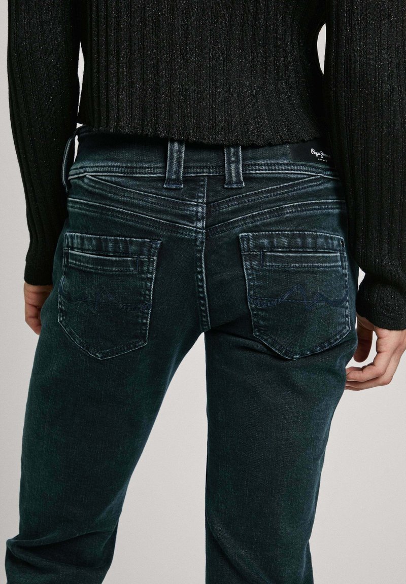Dunkelblaue Jeans aus Denim mit einer taillierten Silhouette, dekorativer Nähten an den Taschenkanten und einem leichten Verblassen auf der Rückseite.